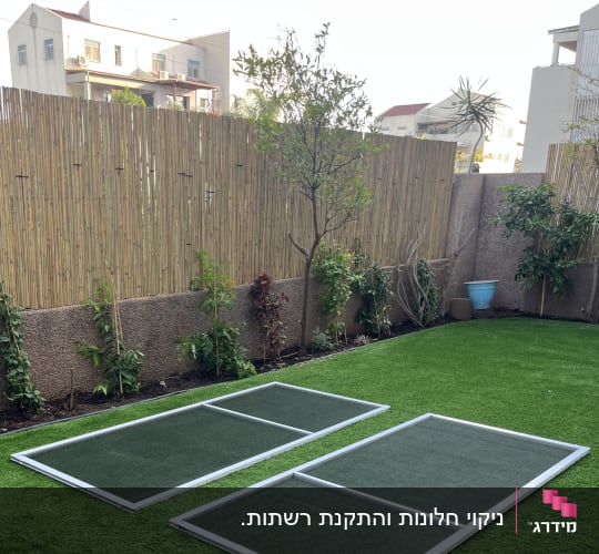 רשתות חלון ויטרינה מפורקות ומונחות על הדשא בגינה לצורך ניקוי